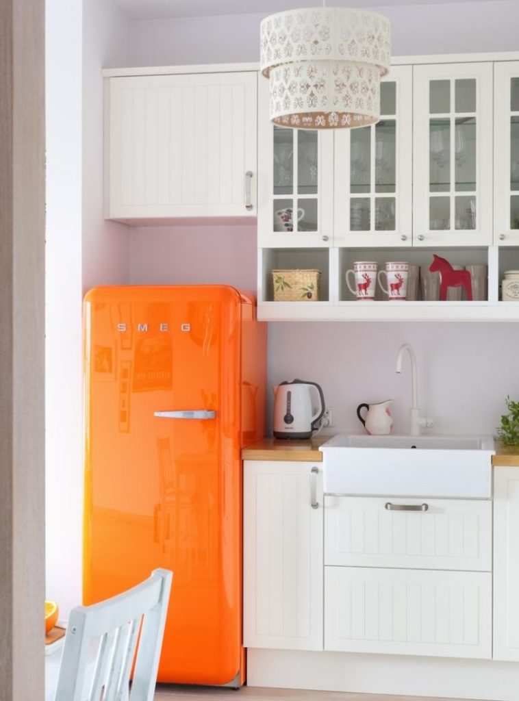 Réfrigérateur orange dans la cuisine avec des meubles blancs