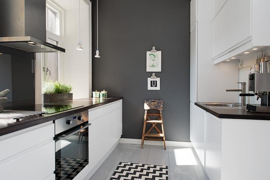 Meubles blancs dans une cuisine étroite avec un mur gris