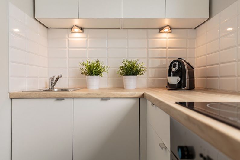 Kompakt bir mutfakta asılı dolapların altında küçük lambalar